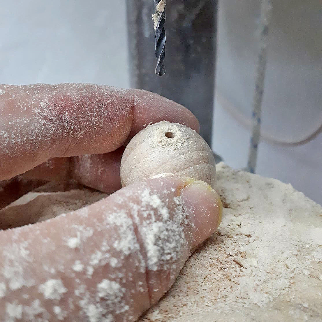 manos perforando una bola de madera