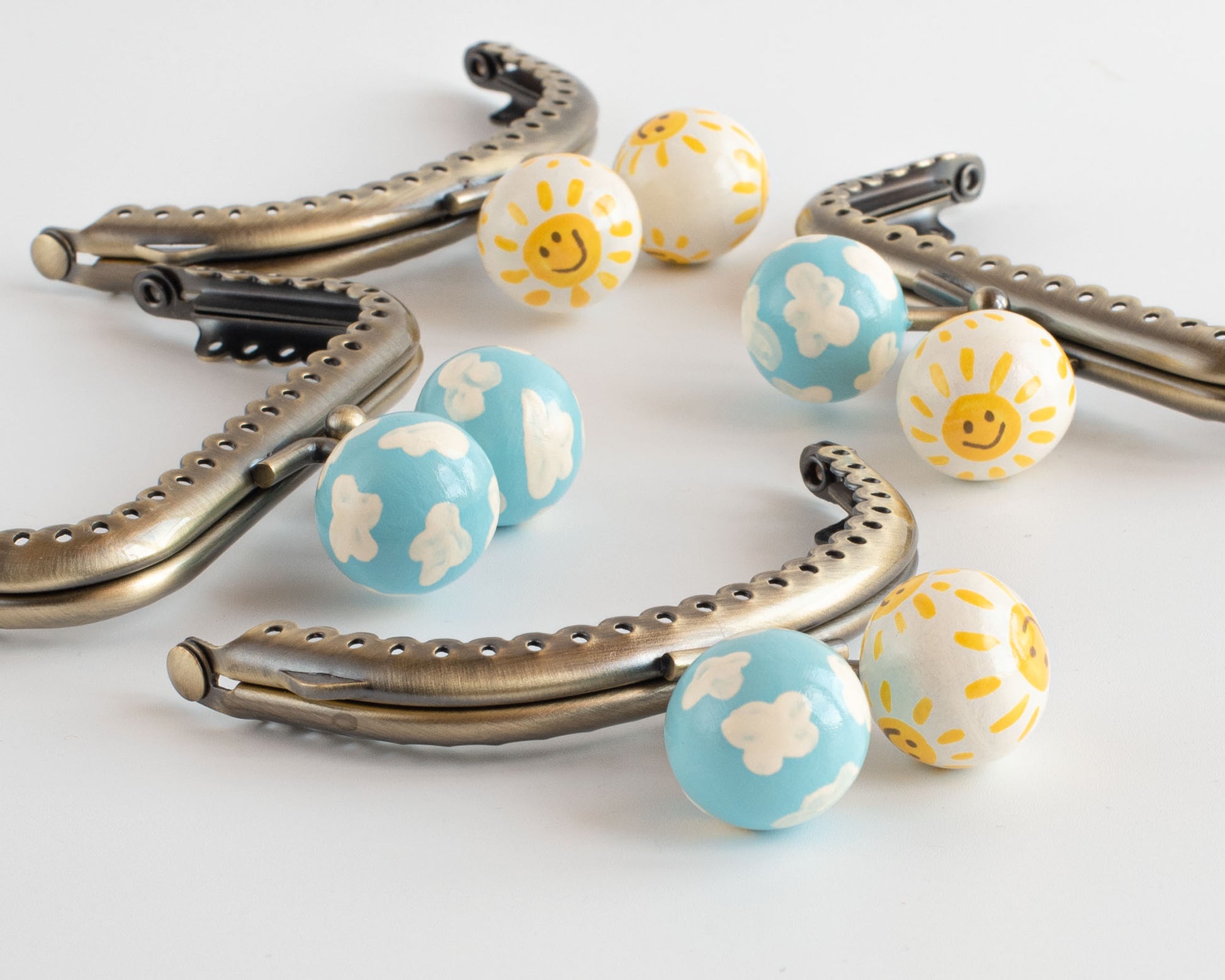 grupo de boquillas para monederos con bolas decoradas pintadas a mano con soles sonrientes y nubes blancas
