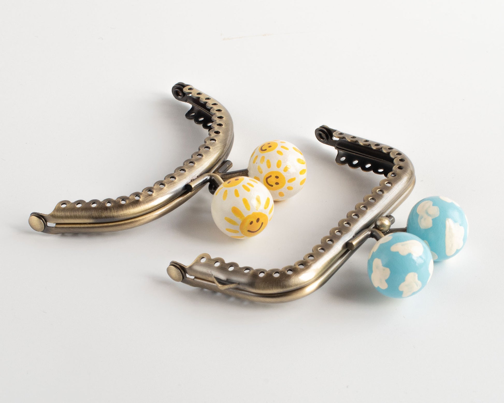 pareja de cierres de boquilla para monederos hechos a mano con soles amarillos que sonrien y nubes blancas sobre cielo azul