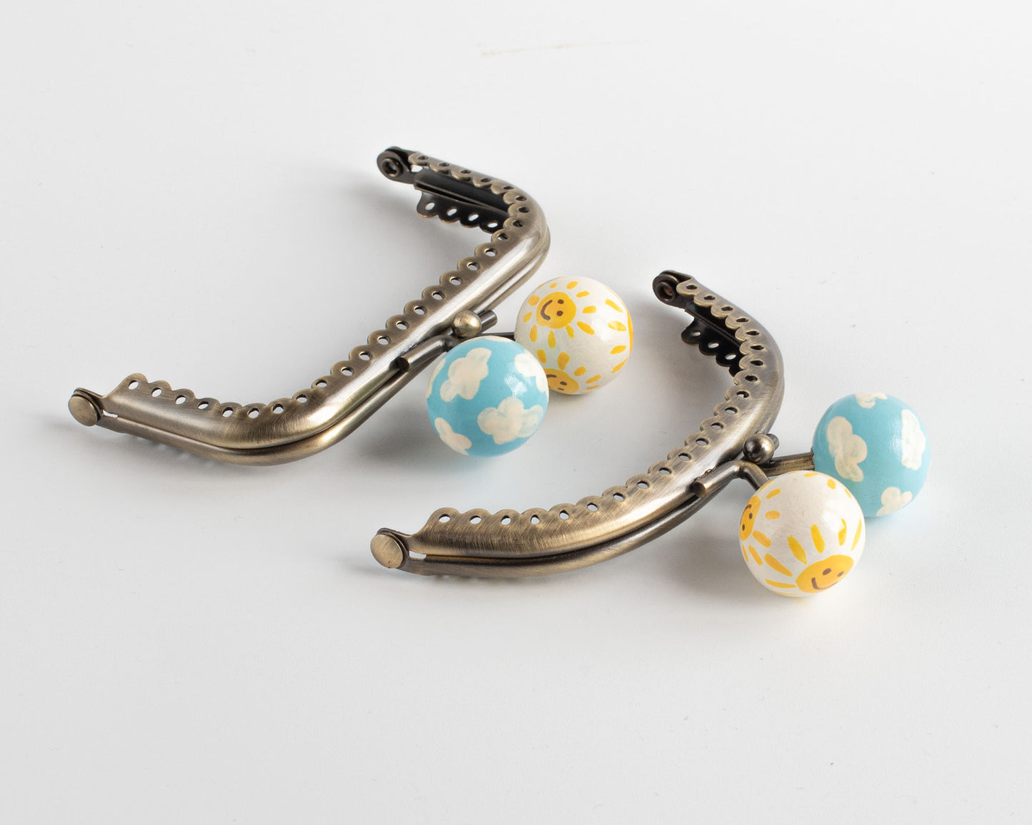 cierres para monederos y bolsos decoradas a mano con dibujos de soles felices y nubes en cielo azul
