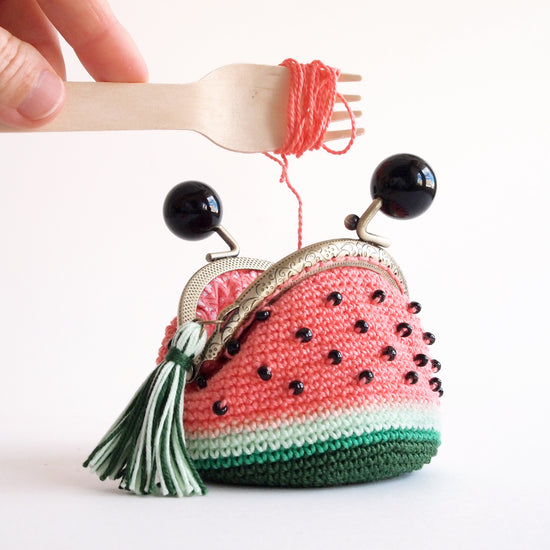 foto creativa de un monedero tejido en crochet con forma de sandía con boquilla redonda de metal