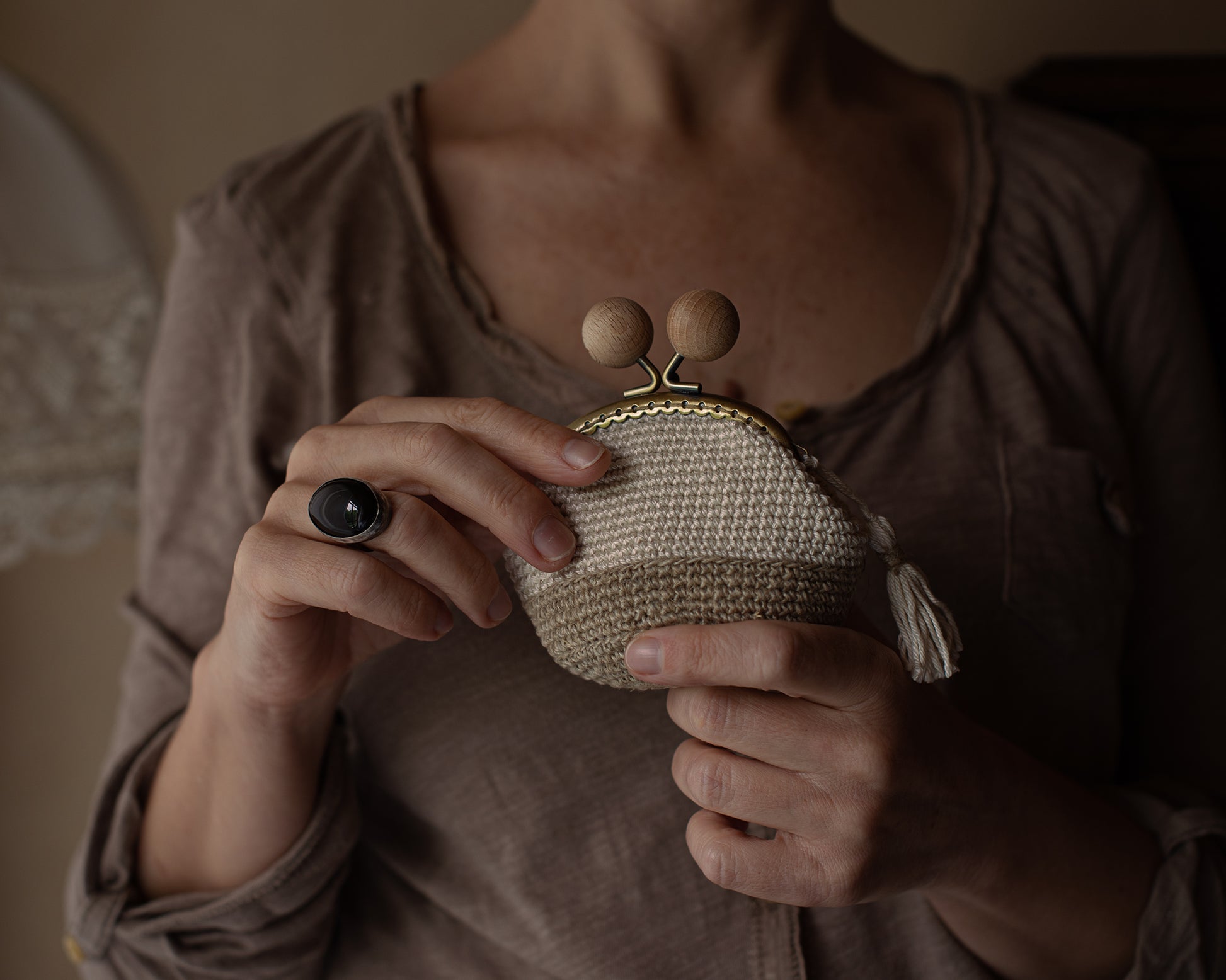 Mujer muestra un monedero de crochet hecho por ella en un entorno rústico
